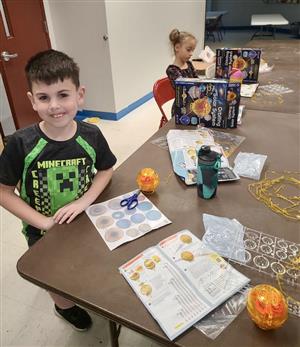Children smile as they build solar system kits