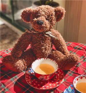 Teddy bear is posed with a cup of warm tea