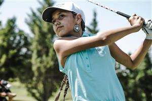Young female golfer watching her ball fly.